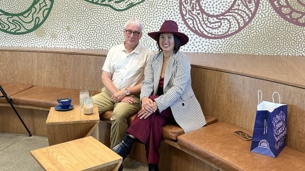 David Brancaccio and Juanny Romero pose for a photo on a wooden bench at Mothership Coffee Roasters.