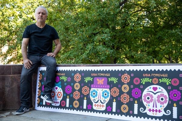 A man sits with a large poster.