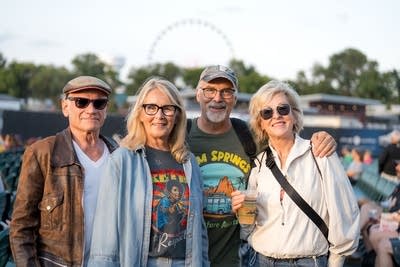 Four people pose for a photo ahead of a concert at an outdoor music venue