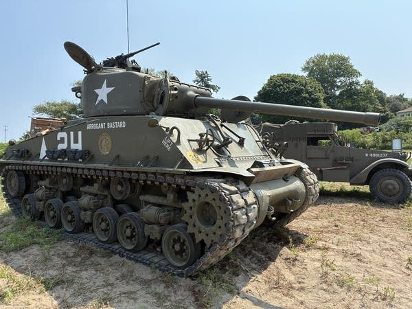 A military tank stands by before the main event. It is large enough that it requires four people to operate it.