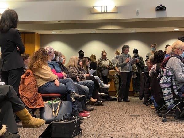 People listen to testimony in public meeting