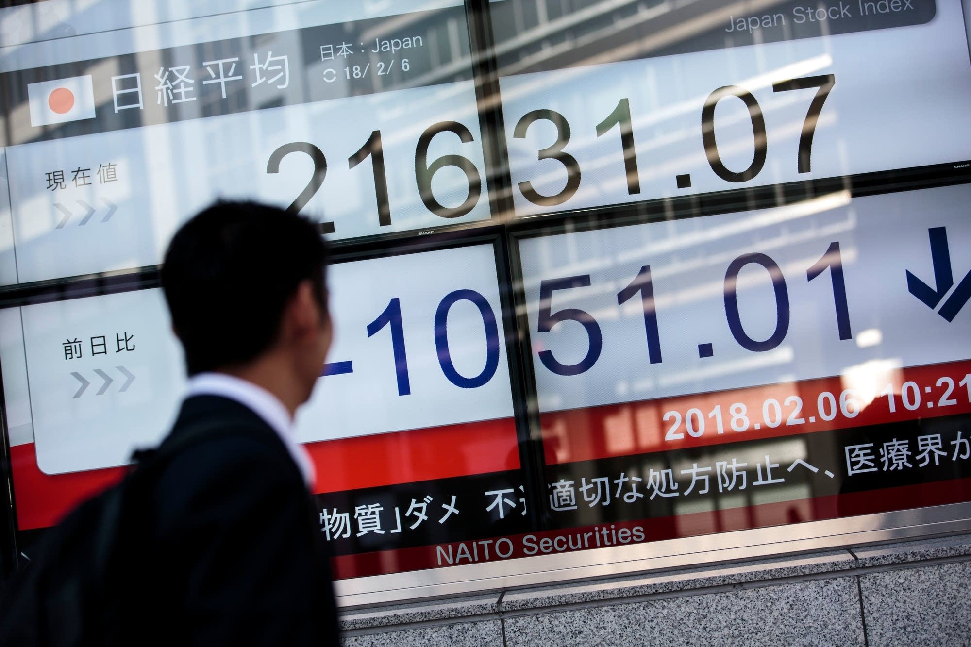 A man walks past an electronics stock indicator in Tokyo.