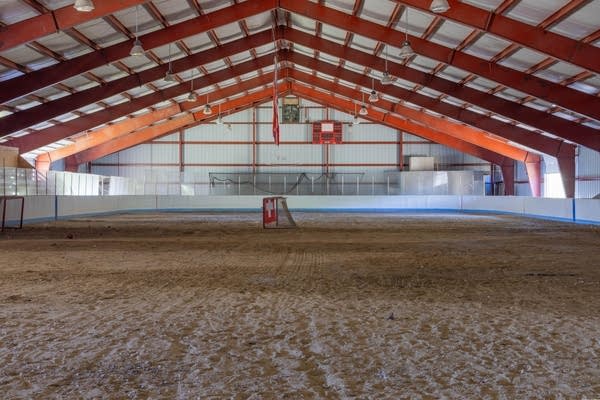A view of a large ice arena with sand and two hockey goals.