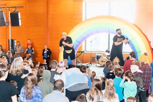 Children and adults watch a live performance by a vocal duo