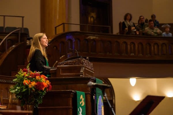 A woman preaches from a pulpit.