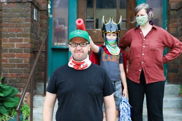 A man stands in front of a woman and child dressed in costume. 