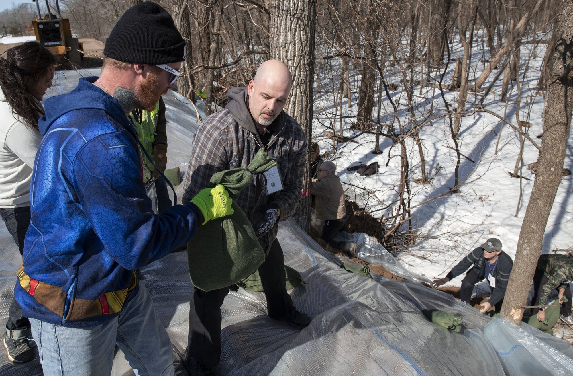 James Hause and Matt Olson use sandbags to hold down plastic on a berm.