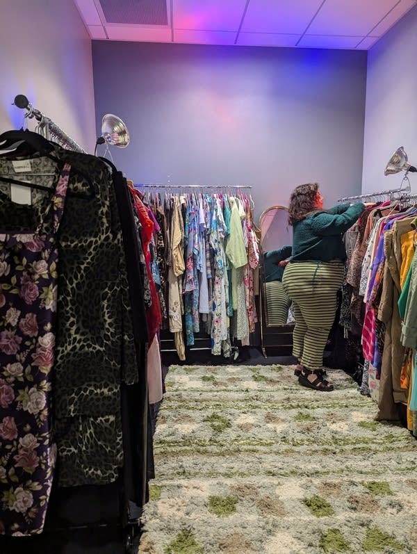 A person hangs an item on a rack inside a clothing shop.
