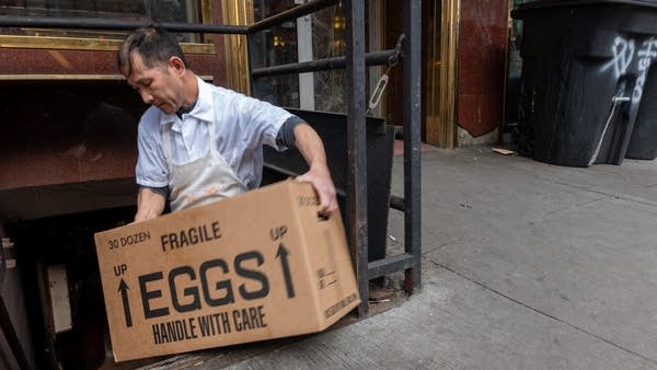 A restaurant worker moves a box of eggs.