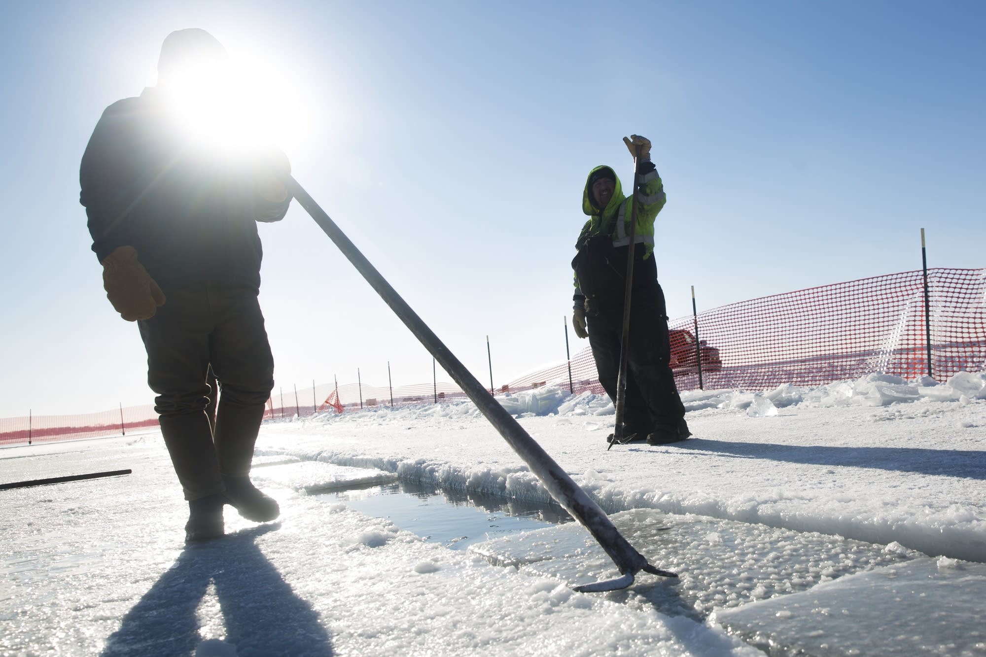 A volunteer uses an ice pick to push blocks of ice.