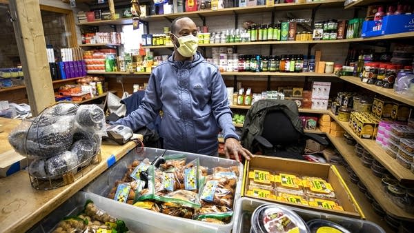 A man wearing a mask at a counter in a store. 