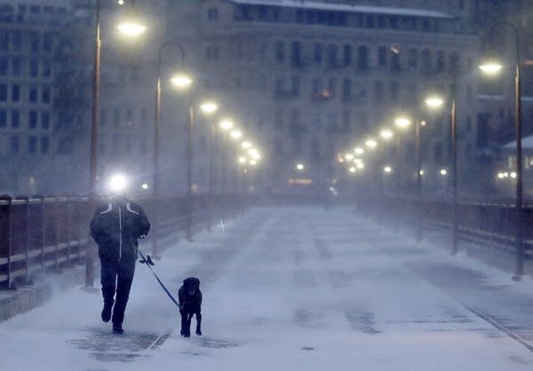 A runner and his dog brave frigid conditions across the Stone Arch Bridge, Thursday, Jan. 24, 2019, in Minneapolis.