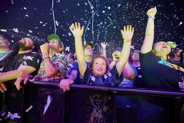 Music fans, including kids, cheer as confetti and streamers fly through the air