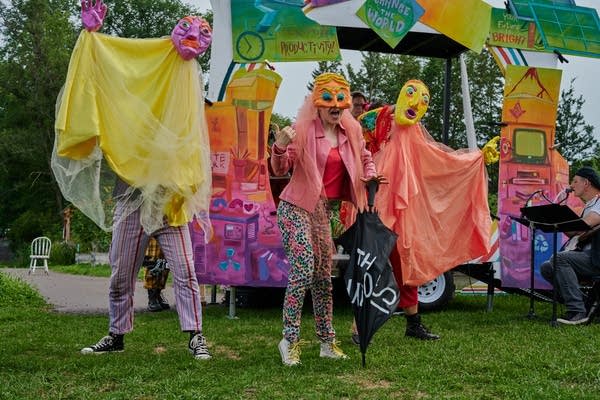 A group of people perform in colorful clothes and costumes outdoors.