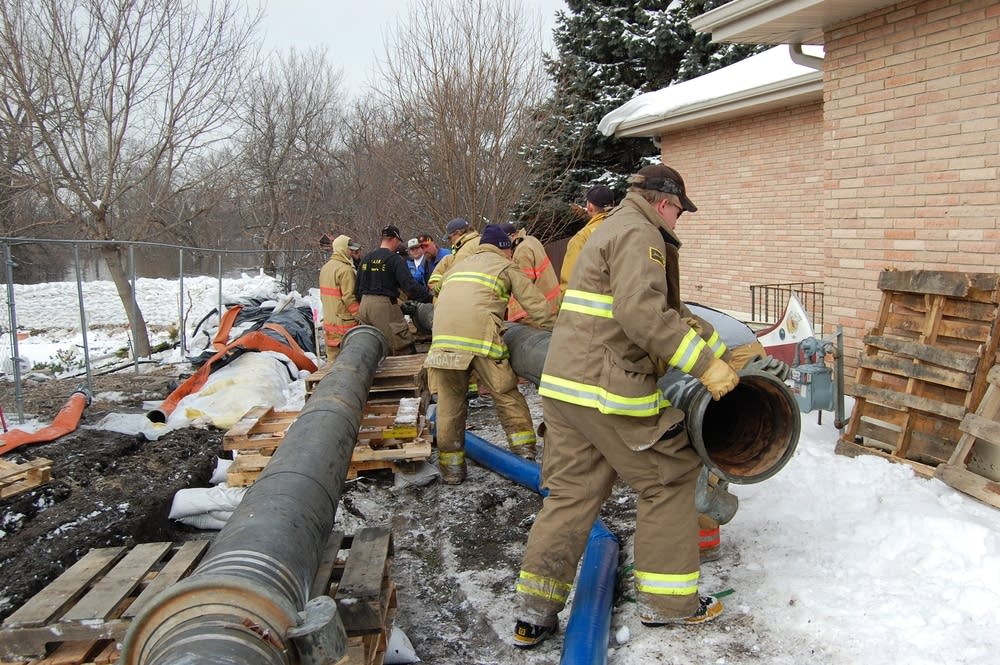 Firefighters work to install pipe for a new pump