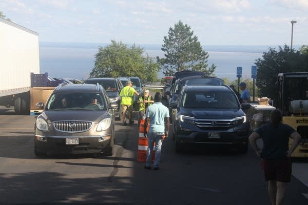 Workers direct cars through a pickup line for food.