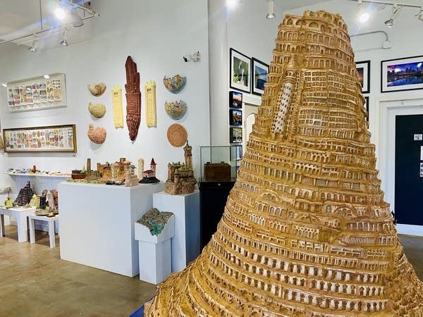 A large sculpture of a spiral tower sits in the middle of an art gallery.