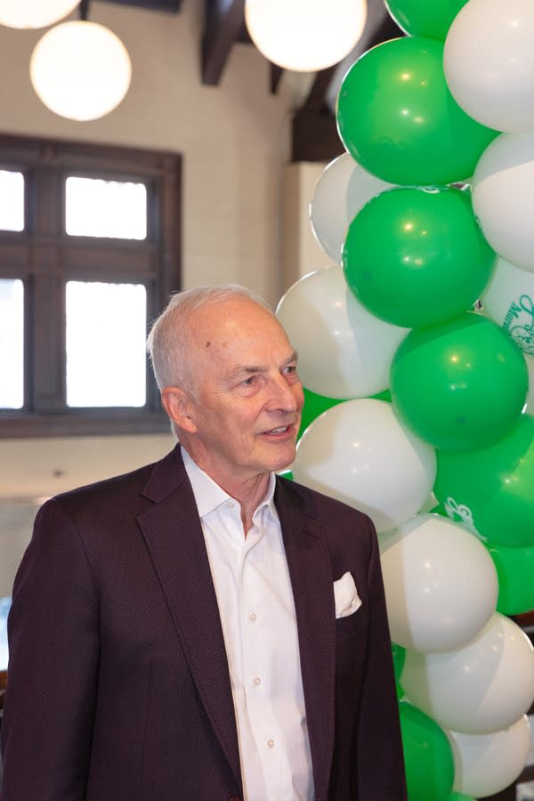 Man stands by balloon arch