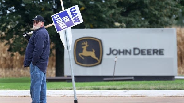 A striking worker pickets a John Deere facility in Davenport, Iowa. The current labor shortage is making it harder to pay new workers less than those already employed. 