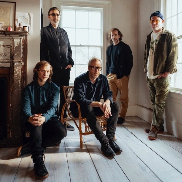 Five men gathered for a portrait in a room of a rustic house