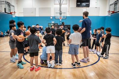 A group of young basketball players listen to their coach.