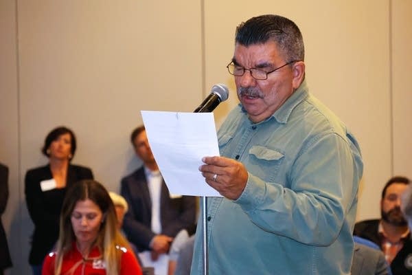 A man reads of a piece of paper and talks