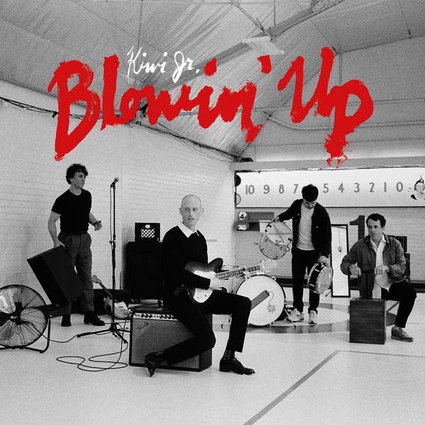 Four musicians set up instruments in the corner of a gym