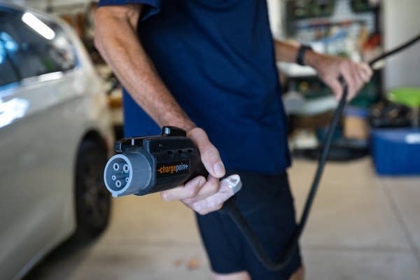 A person holds an EV charging cable