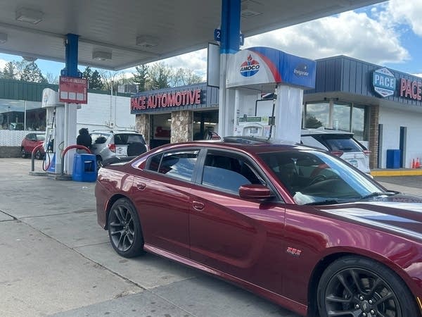 A red sportscar is parked at a gas pump.