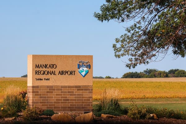 A concrete sign reading "Mankato Regional Airport" is seen in front of a field.