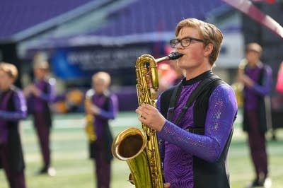 A marching band performs on the field of a football stadium.