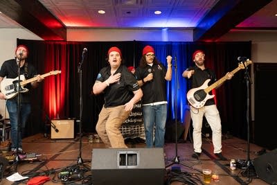 Four men wearing red beanies performing