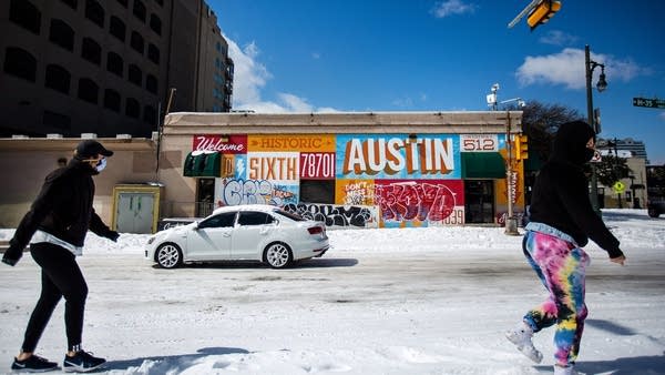 Pedestrians walk on along a snow-covered street on February 15, 2021 in Austin, Texas.