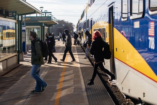 People step off of a train onto a platform.