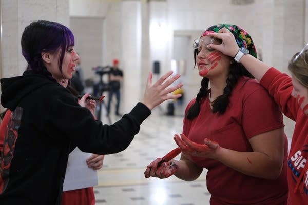 Two protesters applying paint to the other's faces