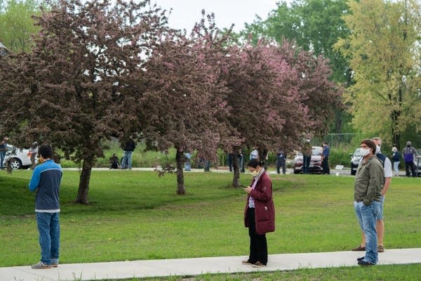 People stand in line with distance between them.