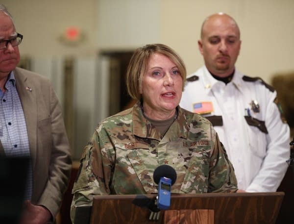 A woman in a uniform speaks in front of a microphone. 