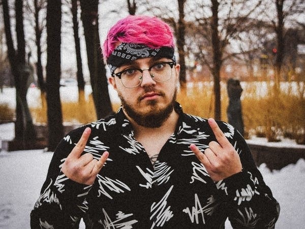 A man with his hair dyed pink poses for a photo