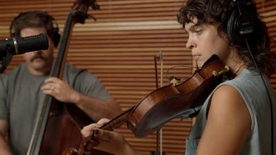Two musicians play stringed instruments in a recording studio