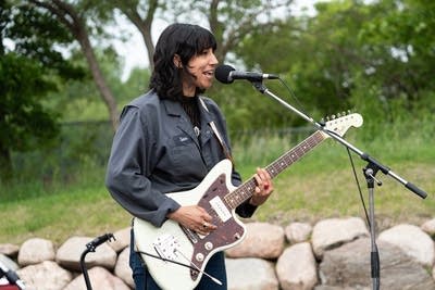 A musician sings and plays guitar at an outdoor venue