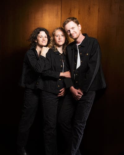 Three people sit close together.
