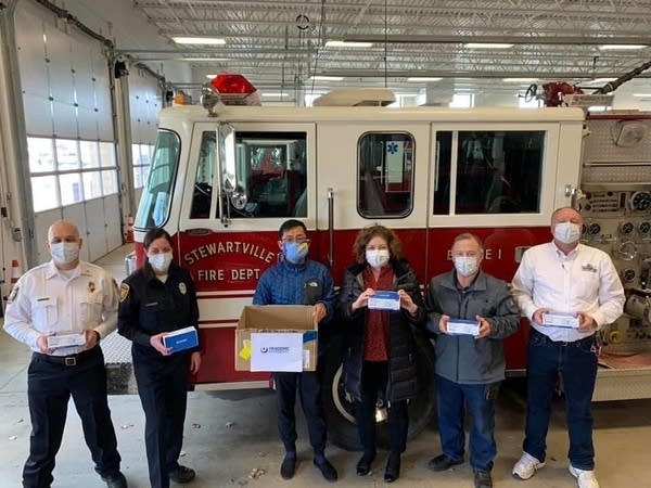 A group of people stand in front of a firetruck.