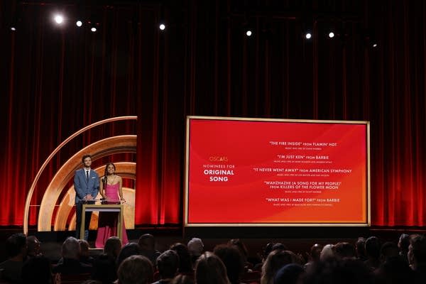 Two people onstage announcing awards nominees