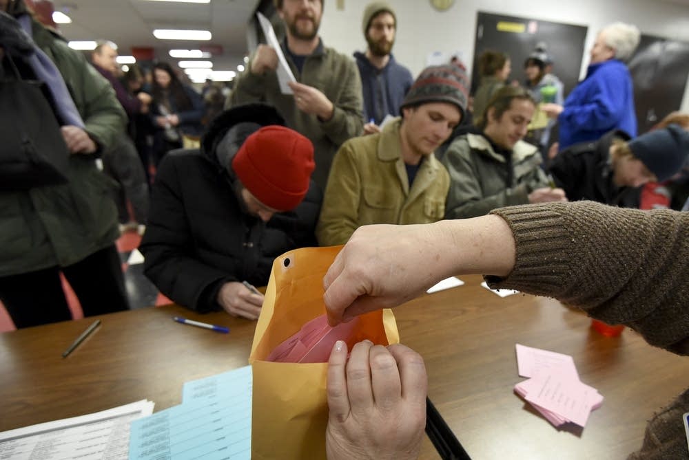 A caucus volunteer stuffs ballots.