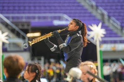 A marching band performs on the field of a football stadium.
