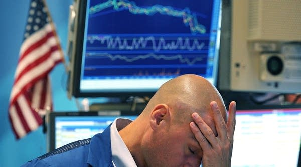 A trader holds his head while working on the floor at the New York Stock Exchange.