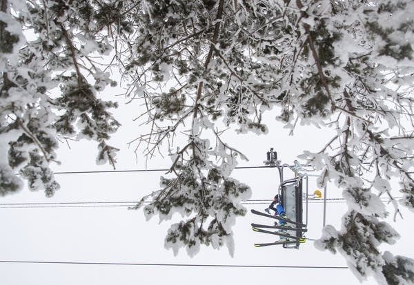 People on a ski lift seen through trees