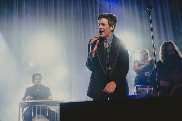 A musician sings onstage in a large music venue