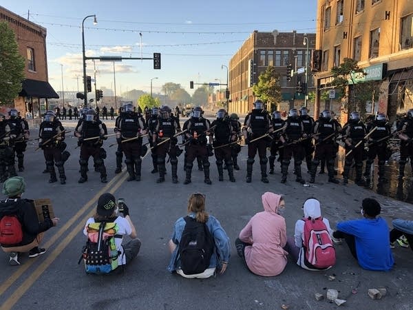 Demonstrators sit in the street before a row of police officers in Minneapolis a few days after the slaying of George Floyd. During the protest movement, many activists suffered physical injury and financial loss. 