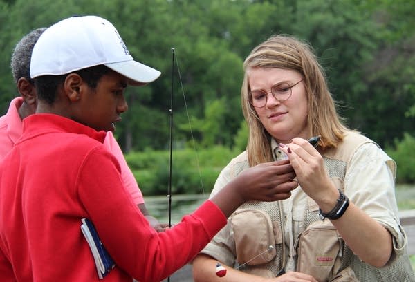 MinnAqua Intern Gabby Travers, right, helps Ishmael Diriye remove a fish.